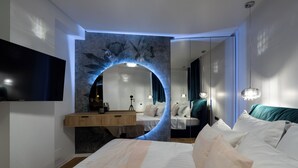 A modern bedroom with a large bed, a vanity with a mirror, and a flat-screen TV mounted on the wall. - Manu Art Living (Bucharest)