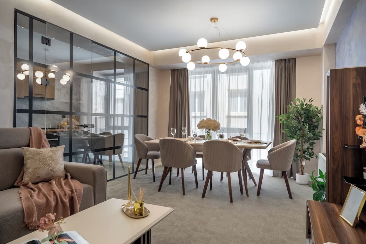 Una sala de estar moderna con comedor, ventanas amplias y una araña.