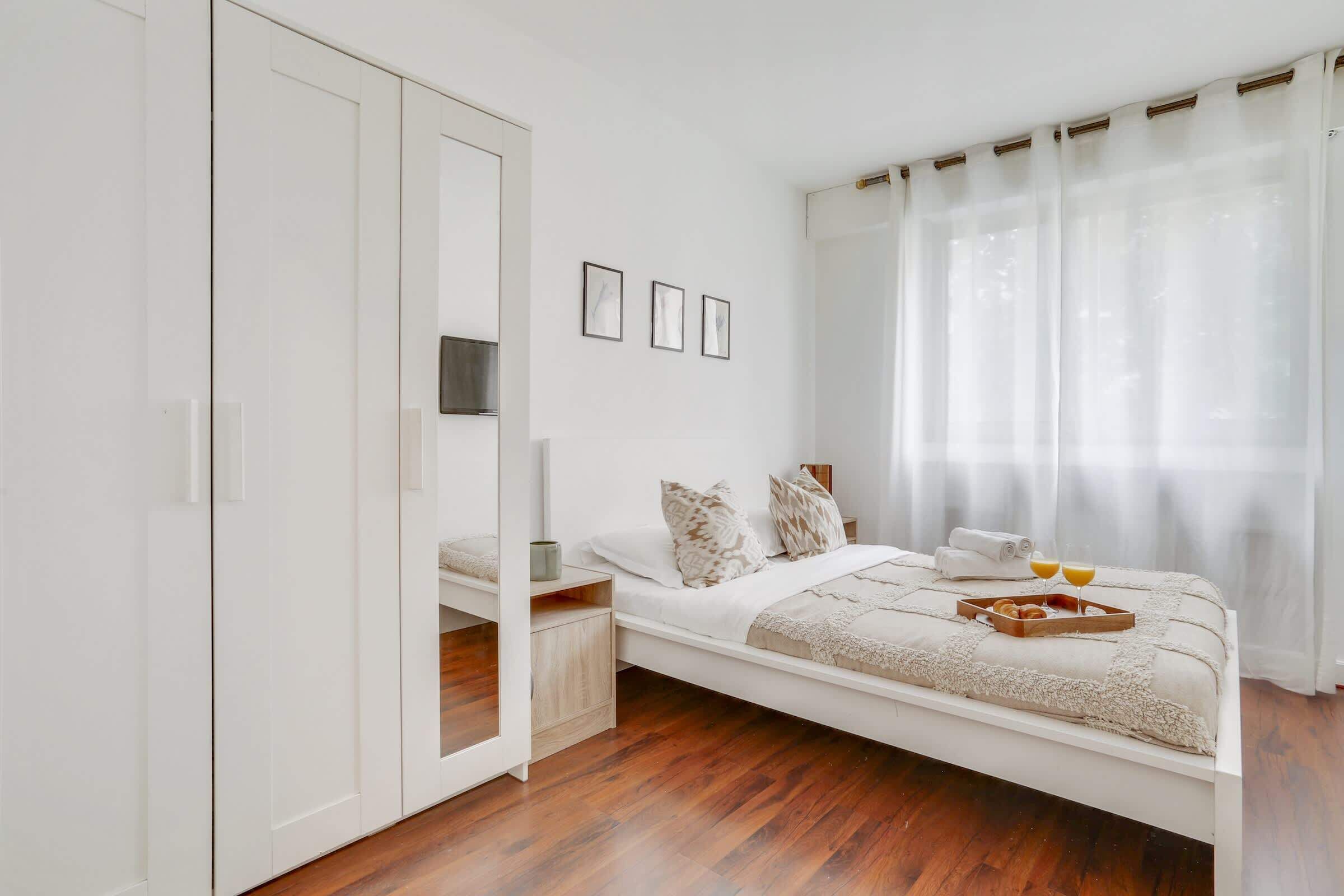 Ein Schlafzimmer mit einem Bett, einem Kleiderschrank und einem Fenster mit Vorhängen.
