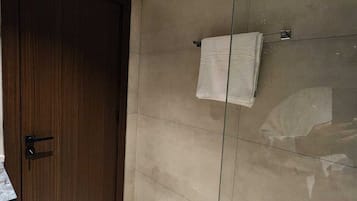 A modern bathroom with a wooden door, tiled walls, and a glass shower enclosure.