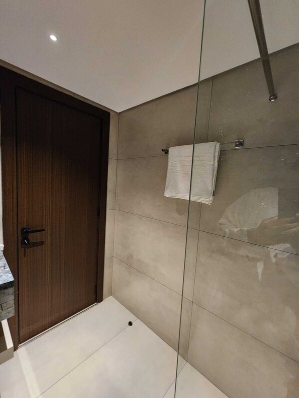 Un baño moderno con puerta de madera, paredes con azulejos y cabina de ducha de vidrio.