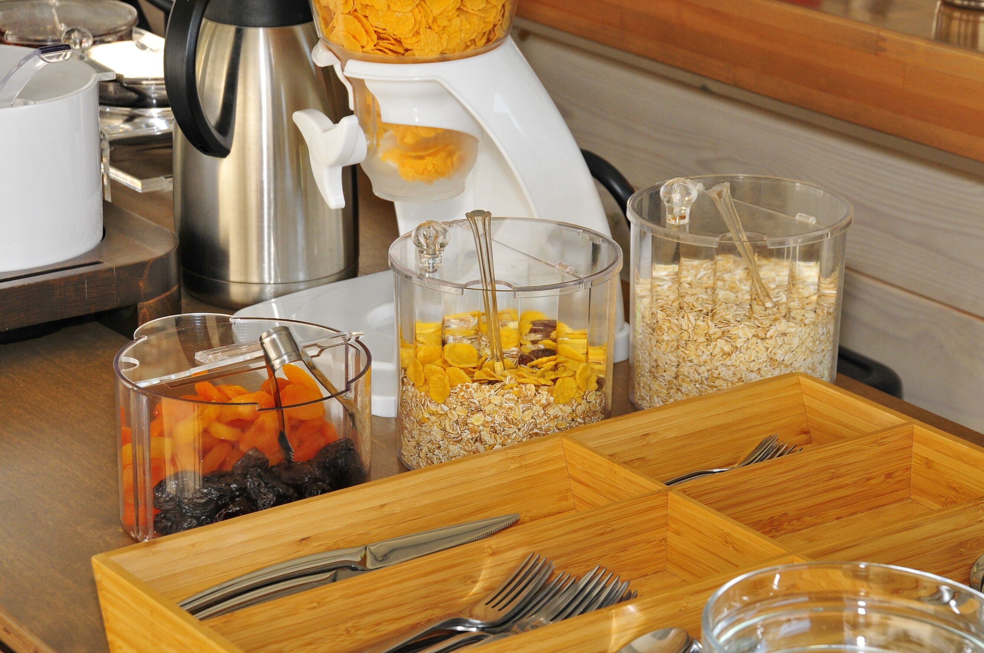 Montaje de un bufé de desayuno con diversos alimentos y utensilios.