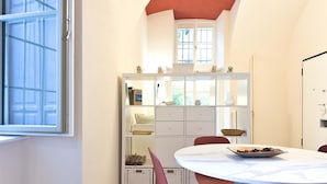 A dining area with a round table, chairs, and a white cabinet with shelves. - Loft Portici by Piazza Vittorio (Torino)