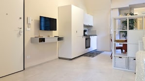 A modern kitchen with white cabinetry, a built-in oven, and a flat-screen TV. - Loft Portici by Piazza Vittorio (Torino)