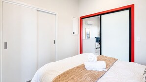 Una camera d'albergo con un letto, uno specchio con cornice rossa, una porta bianca e una parete bianca.