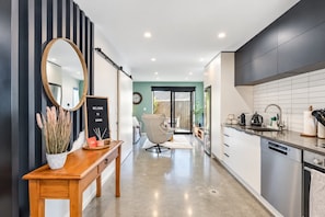 A modern kitchen with a stainless steel refrigerator, a wooden dining table, and a large mirror.