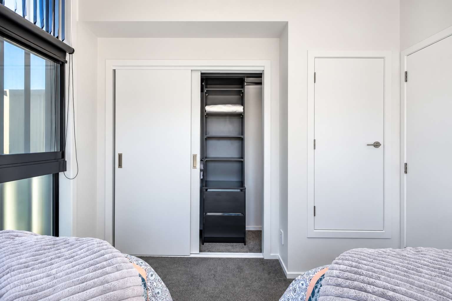 A hotel room with a bed, a closet, and a window.