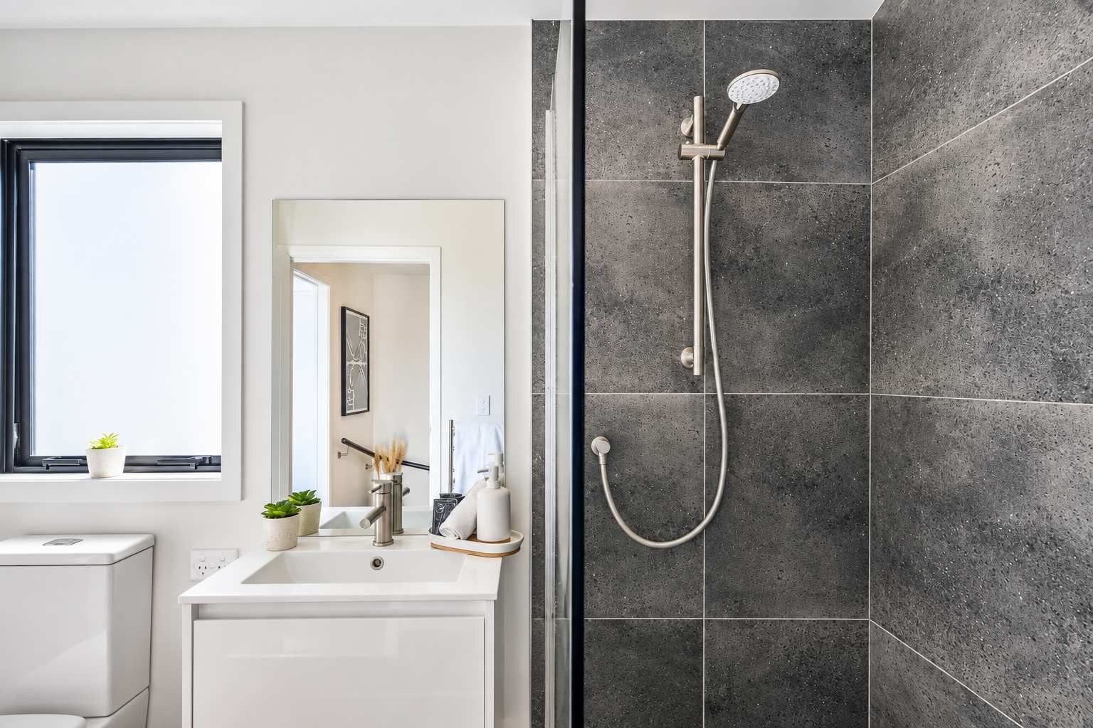 A modern bathroom with a shower, a sink, and a mirror.