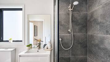 A modern bathroom with a shower, a sink, and a mirror.