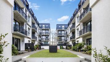 A modern apartment complex with a central courtyard, balconies, and a clear sky.