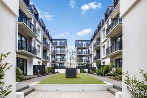 A modern apartment complex with a central courtyard, balconies, and a clear sky. - Newtown Tranquility | 2BR Wellington | Kitchen (Wellington)