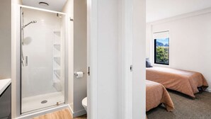 A modern bathroom with a glass shower enclosure, a toilet, and a window with a view of greenery. - Newtown Tranquility | 2BR Wellington | Kitchen (Wellington)