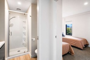 A modern bathroom with a glass shower enclosure, a toilet, and a window with a view of greenery. - Newtown Tranquility | 2BR Wellington | Kitchen (Wellington)