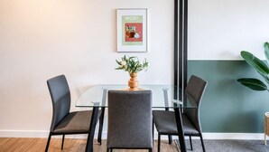 A conference room with a glass table, four grey chairs, a potted plant, and a framed picture on the wall. - Newtown Tranquility | 2BR Wellington | Kitchen (Wellington)
