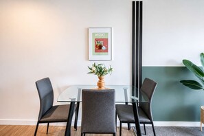 A conference room with a glass table, four grey chairs, a potted plant, and a framed picture on the wall. - Newtown Tranquility | 2BR Wellington | Kitchen (Wellington)