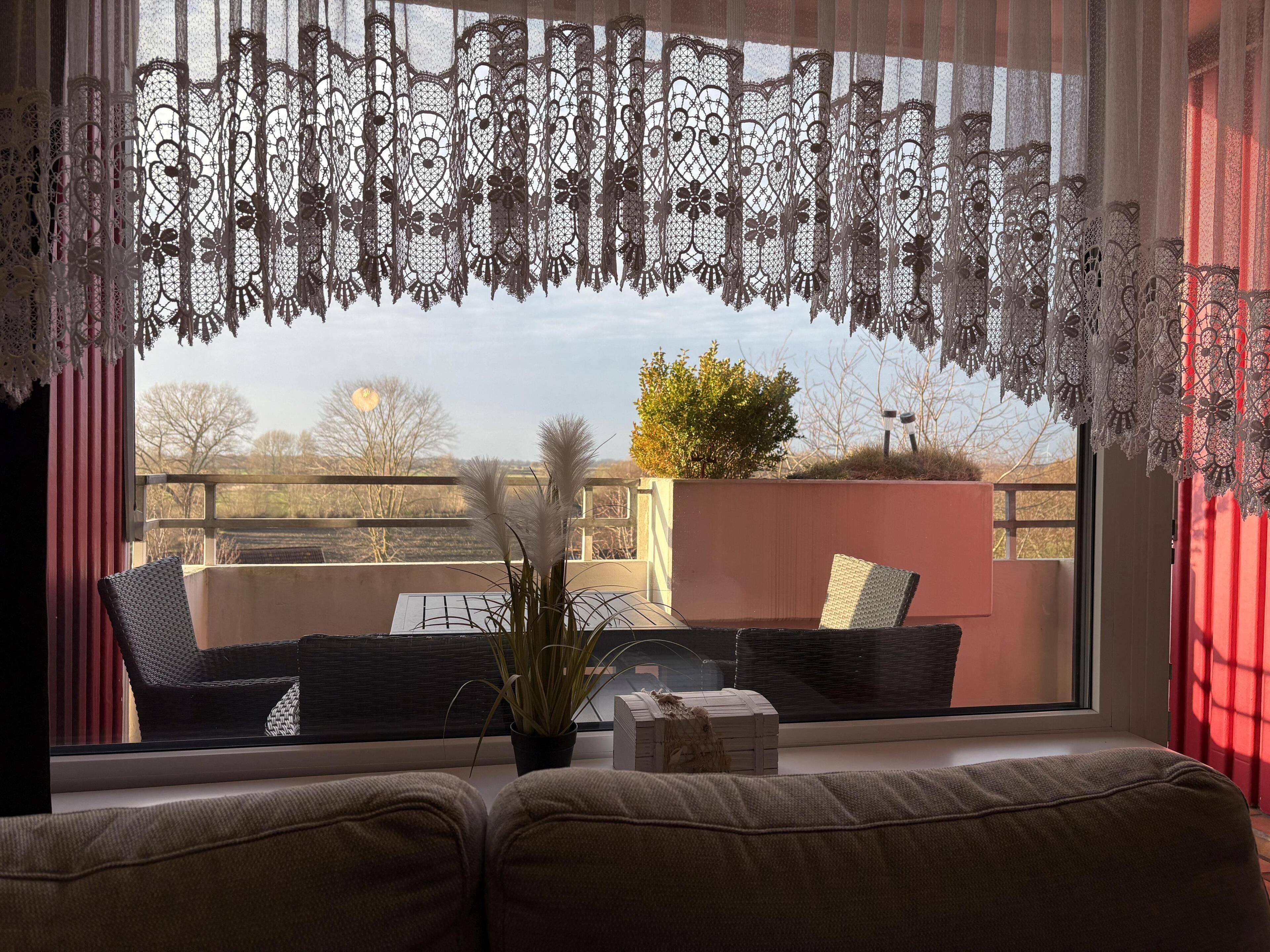 A cozy seating area with a view of a garden and a building across the street.