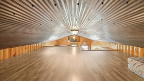 A spacious attic room with wooden walls and a sloped ceiling. - Fishing Pond & Treehouse: Tranquil Maysville Cabin (Maysville)