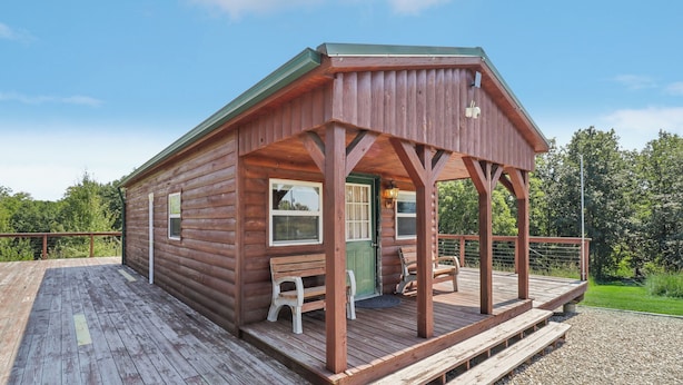 A wooden cabin with a porch, a bench, and a door. - Fishing Pond & Treehouse: Tranquil Maysville Cabin (Maysville)