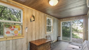 A wooden-paneled room with a wooden chest, a cushioned bench, and a framed fruit artwork. - Fishing Pond & Treehouse: Tranquil Maysville Cabin (Maysville)