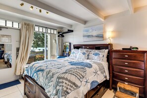 Ein Schlafzimmer mit Bett, Kommode, Nachttisch, Lampe und einem Bild an der Wand.