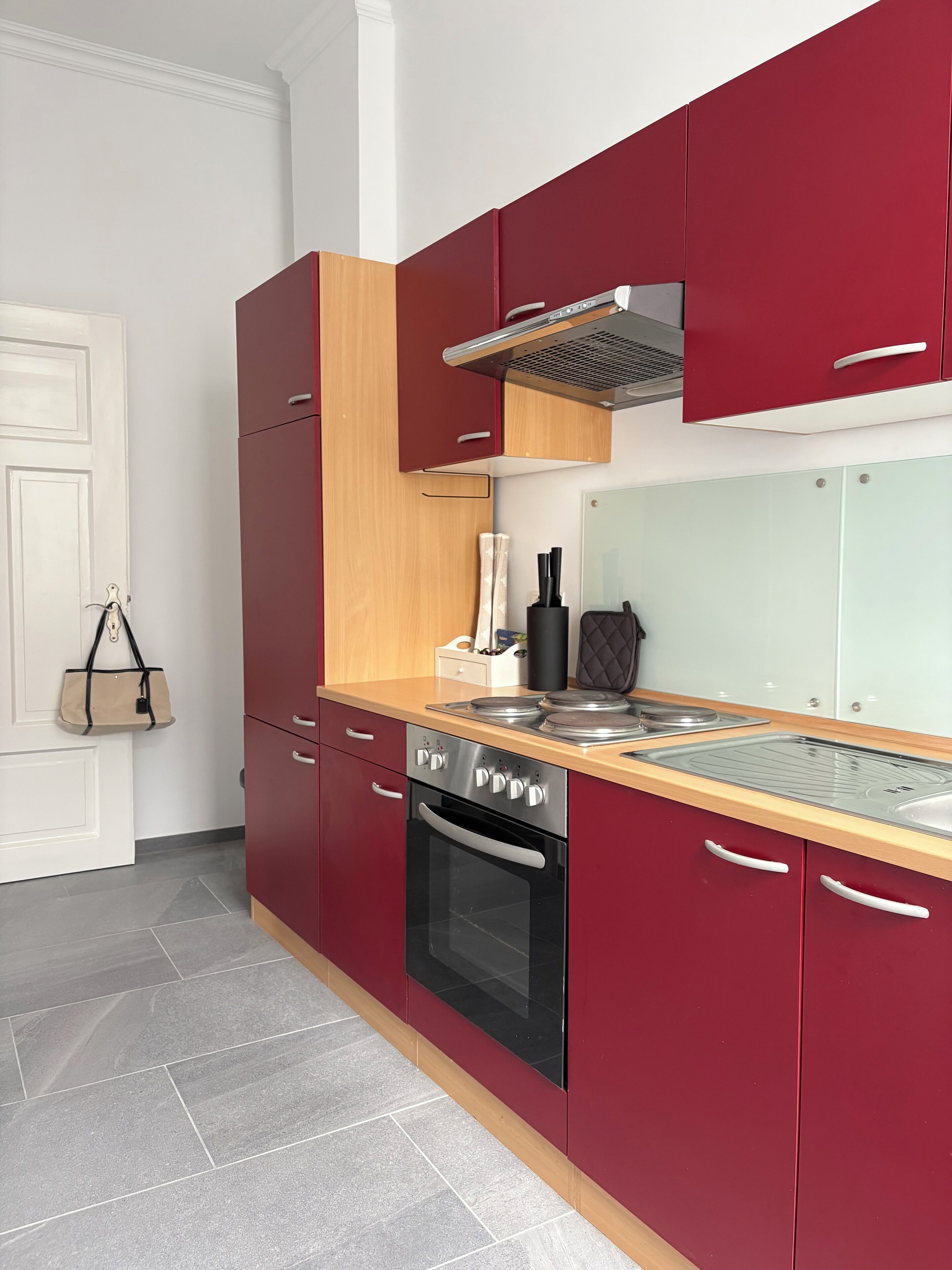 Une cuisine moderne avec des meubles de couleur rouge, une cuisinière en acier inoxydable et un plan de travail en bois.