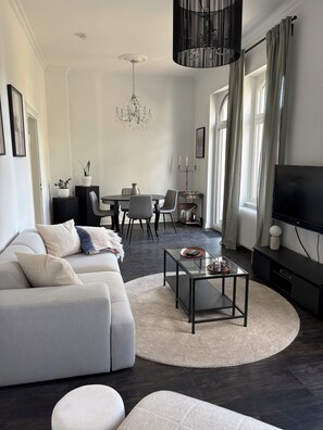 A modern living room with a grey sofa, a glass coffee table, and a TV on a black stand. - Bright apartment with balcony directly opposite the Emser Therme (Bad Ems)