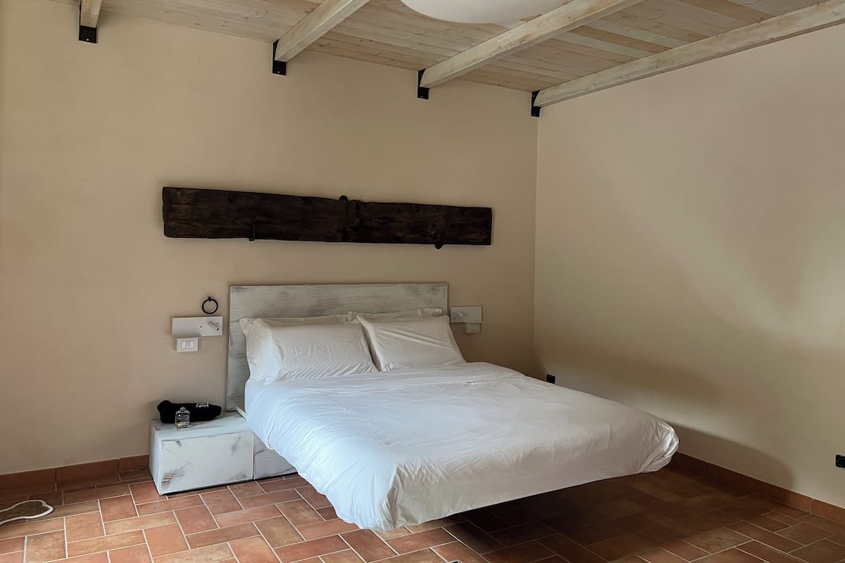 A bedroom with a bed, a nightstand, a wooden headboard, and a ceiling fan.