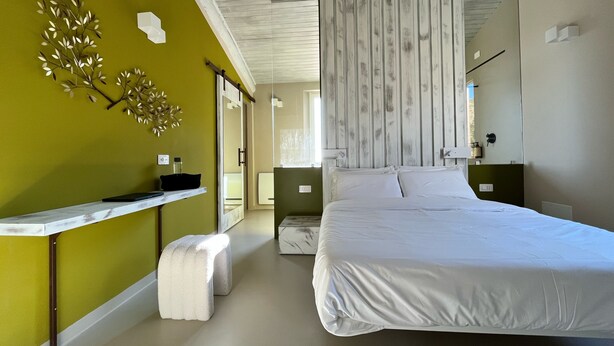 A modern bedroom with a large bed, a bedside table, and a mirror. - Uliveto Magico (Cannara)