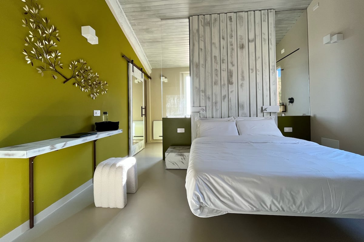 A modern bedroom with a large bed, a bedside table, and a mirror.