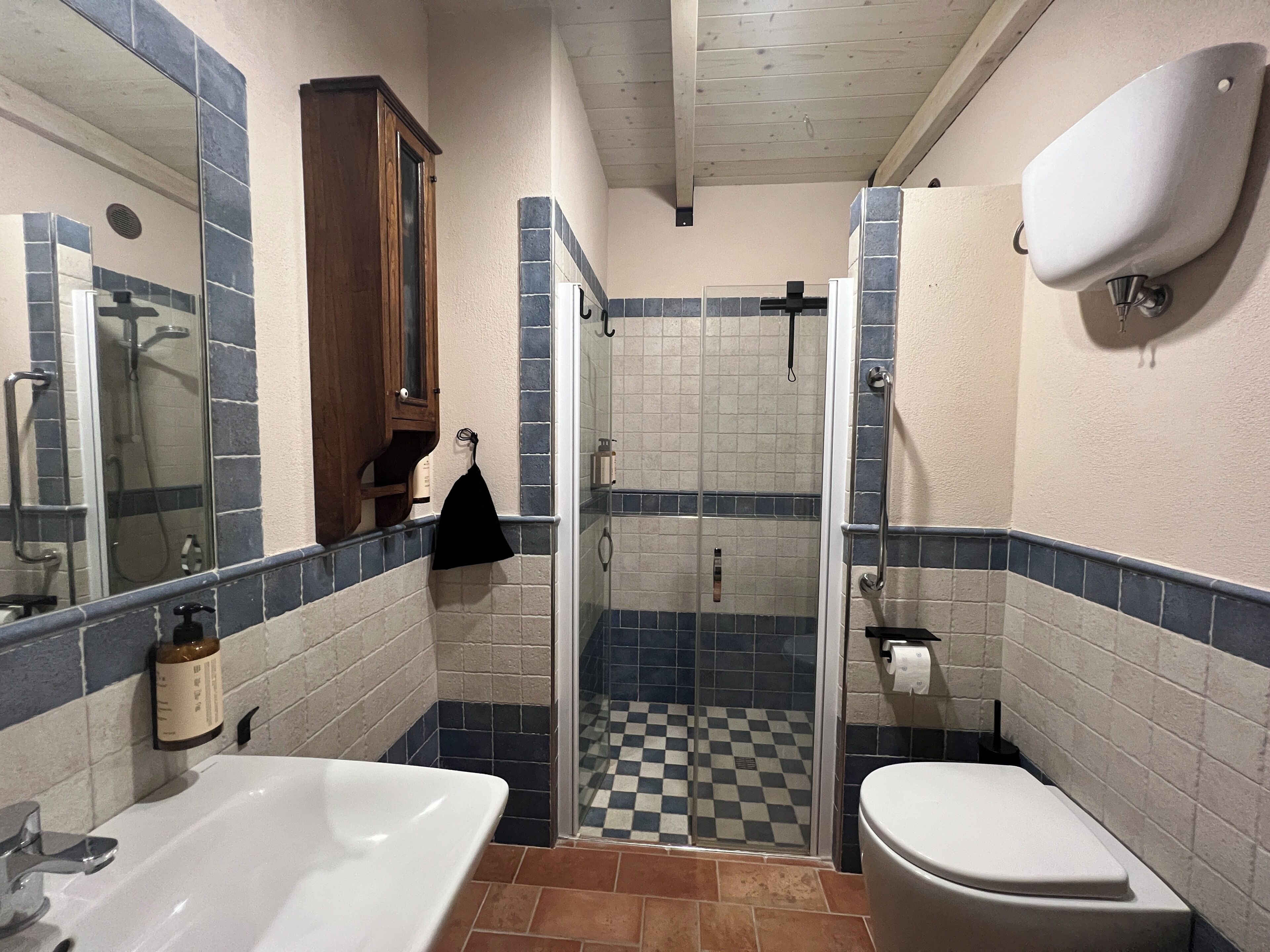 Un baño con ducha, inodoro, lavamanos y espejo.