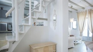A modern interior with a white staircase, a wooden bench, and a dining area with a table and chairs. - Villa Pathos, Apleton Villas Paros (Paros)