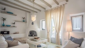 A cozy living room with a fireplace, white sofas, a coffee table, and decorative shelves. - Villa Pathos, Apleton Villas Paros (Paros)