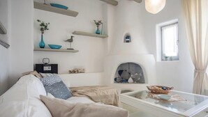 A modern living room with a sofa, coffee table, and decorative items on shelves. - Villa Pathos, Apleton Villas Paros (Paros)