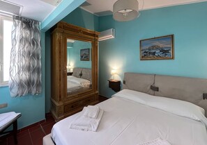 Quarto com uma cama grande, um guarda-roupa de madeira, um espelho, uma mesa de cabeceira com abajur e um quadro na parede.