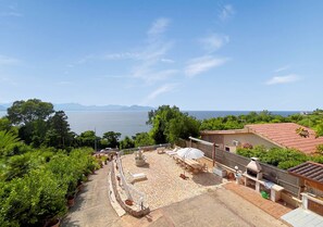 Um terraço no telhado com móveis de exterior, uma fonte de água e vista para o mar.