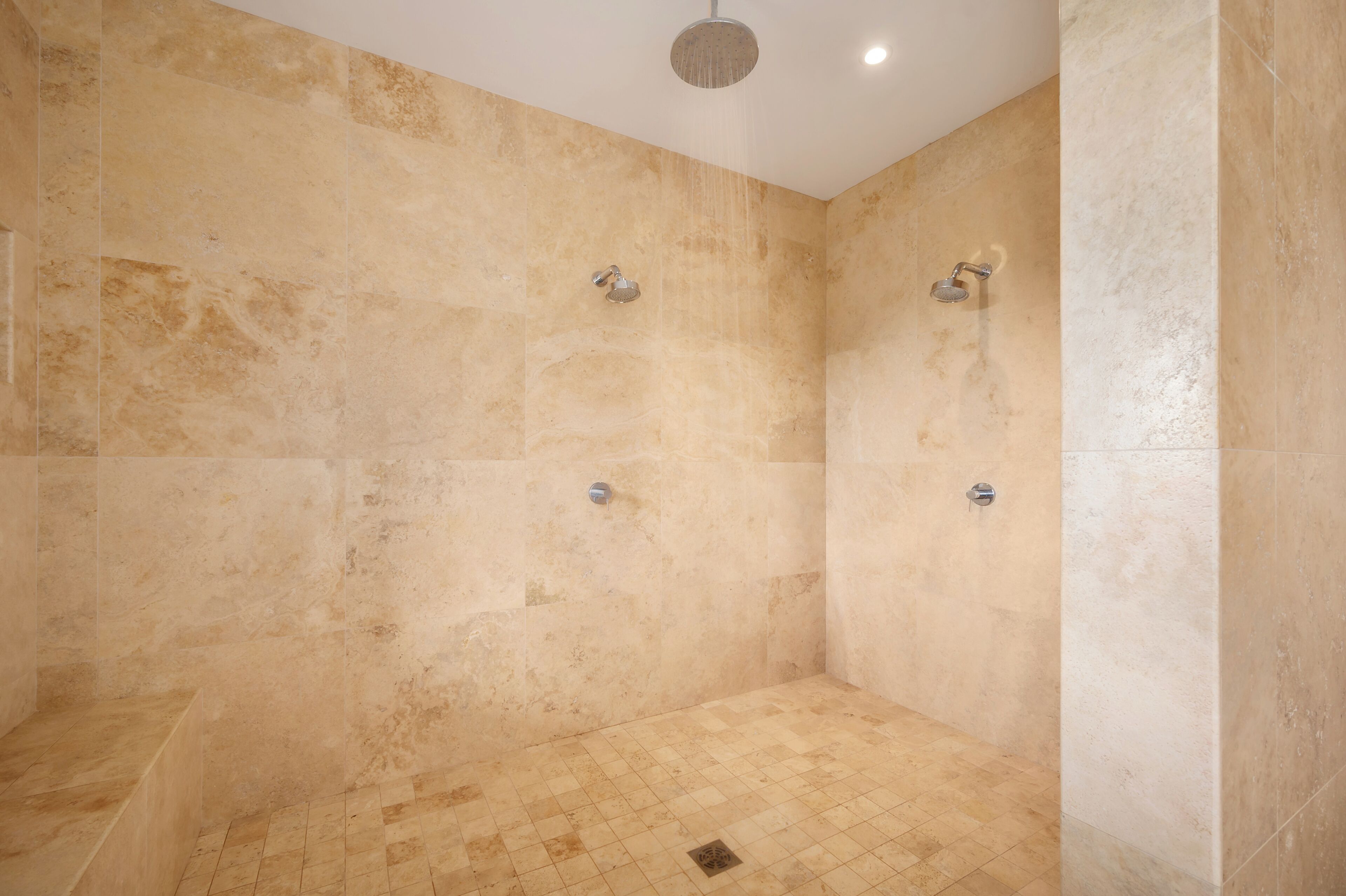 A shower with beige tiles and a single showerhead.
