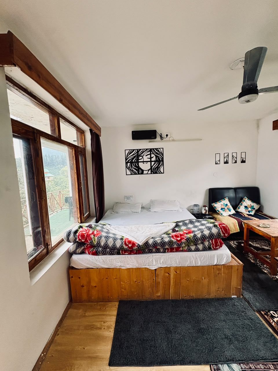 A bedroom with a bed, a desk, a chair, a ceiling fan, and a window.