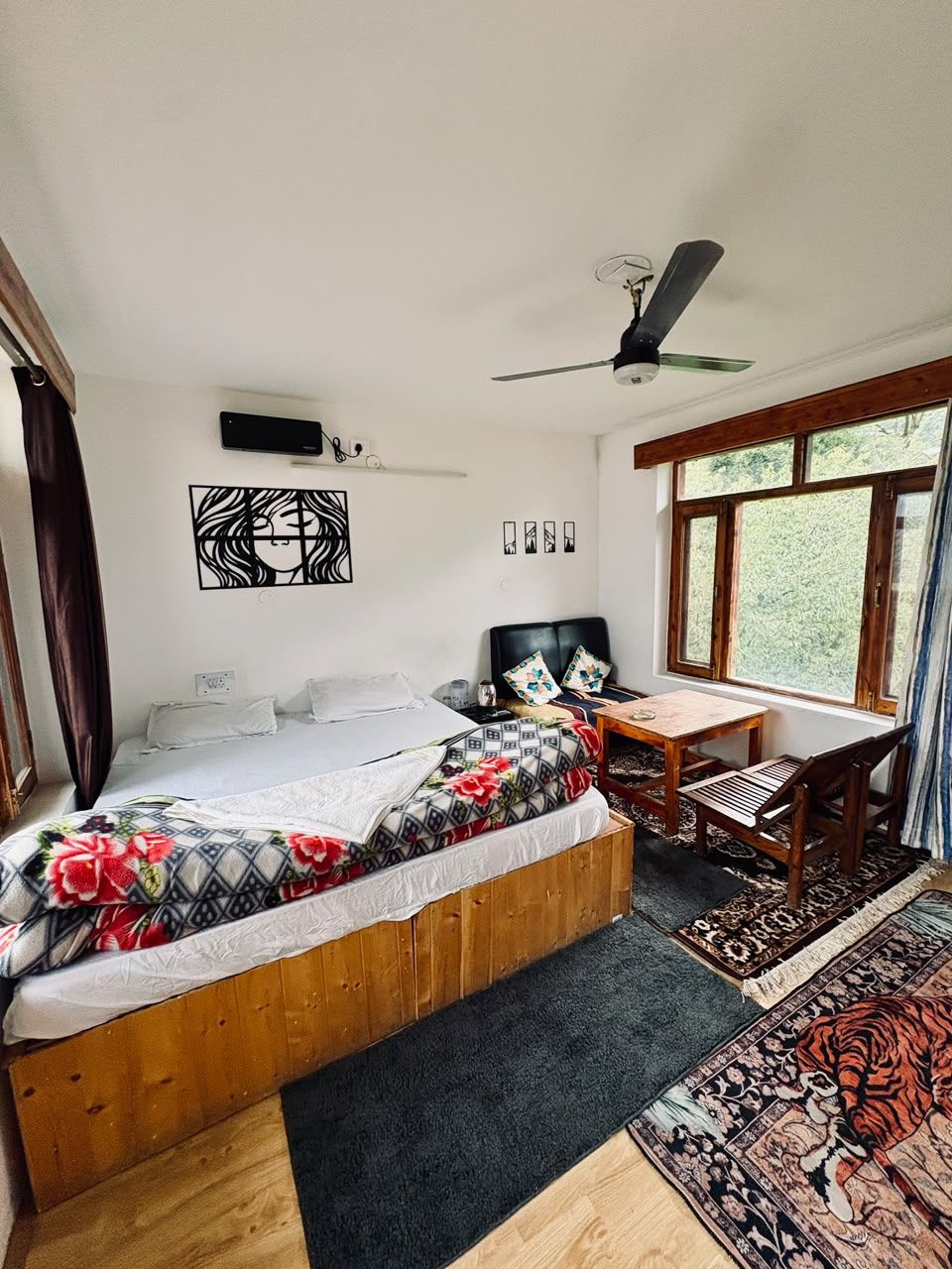 A bedroom with a bed, a desk, a chair, a ceiling fan, and a window.