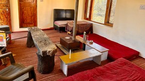 Ein gemütliches Zimmer mit Bett, kleinem Tisch, Bank und Kamin.