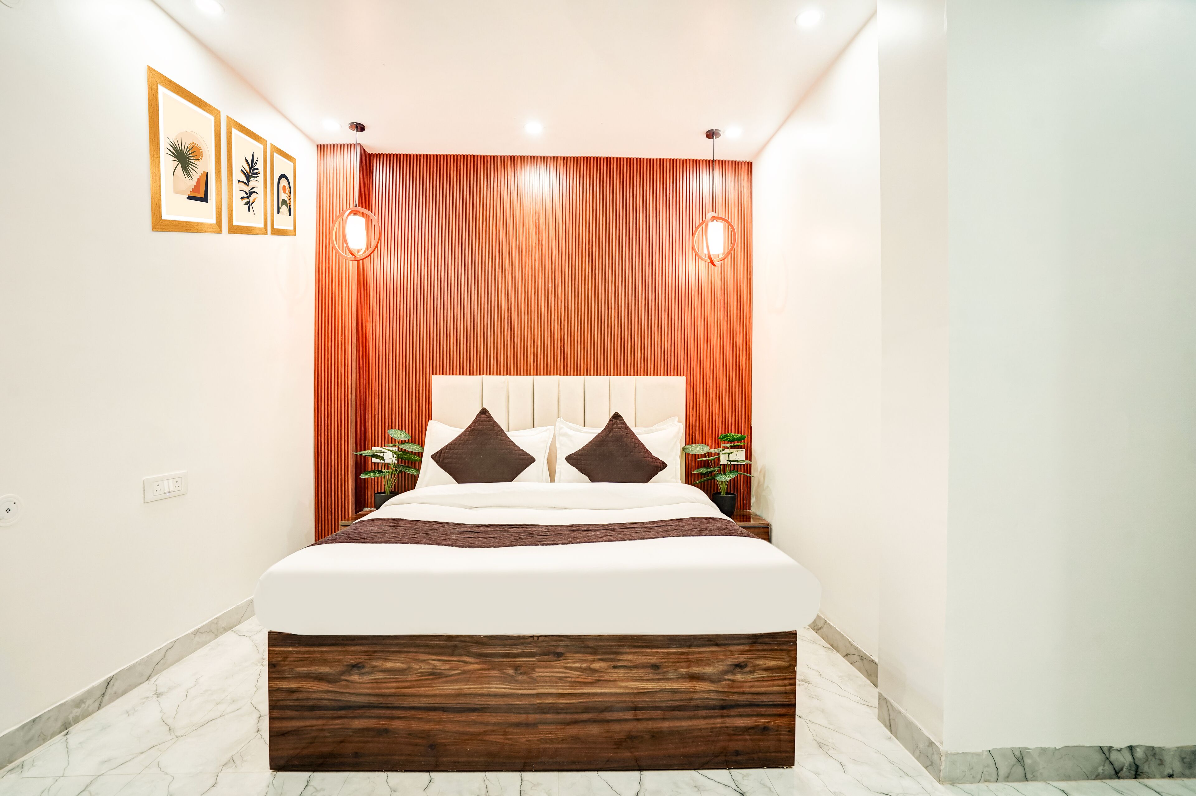 A modern bedroom with a wooden headboard, a large bed, two bedside tables, and a wall-mounted light fixture.