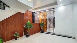 A modern interior with a staircase, wooden paneling, and potted plants. - Hotel Solaris Retreat By The Arrow (New Delhi)