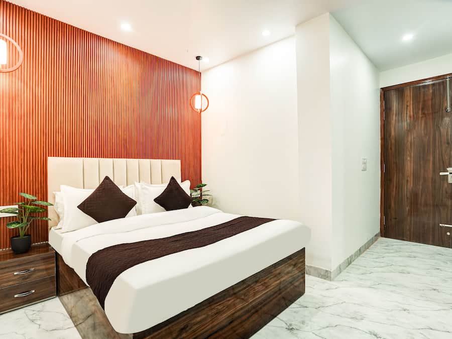 A modern bedroom with a wooden accent wall, a large bed with white bedding, and a marble floor.