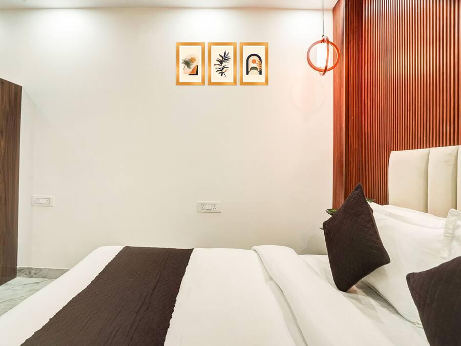 Une chambre d’hôtel moderne, équipée d’un lit, d’une armoire en bois et d’un mur orné de trois tableaux encadrés.
