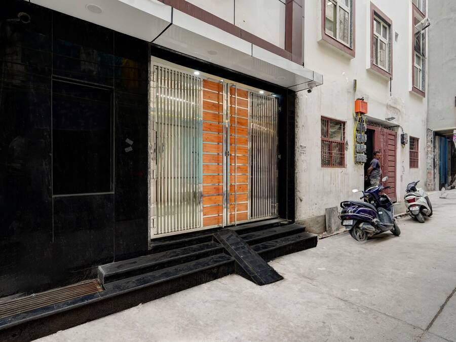 A building with a black entrance door, a set of steps leading up to the entrance, and two scooters parked outside.