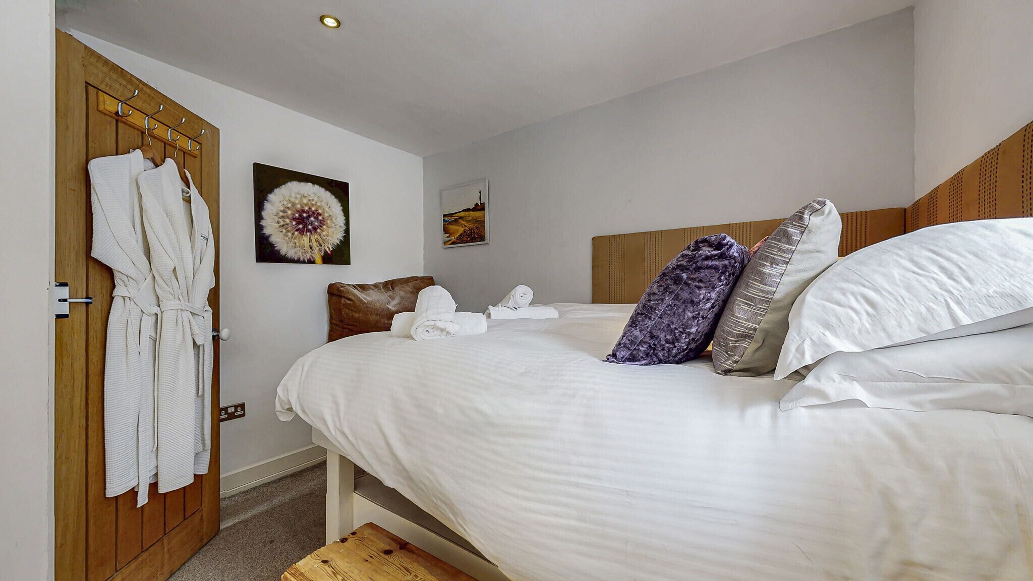 Une chambre d’hôtel avec un grand lit, une tête de lit en bois et une porte en bois dotée d’un porte-serviettes.