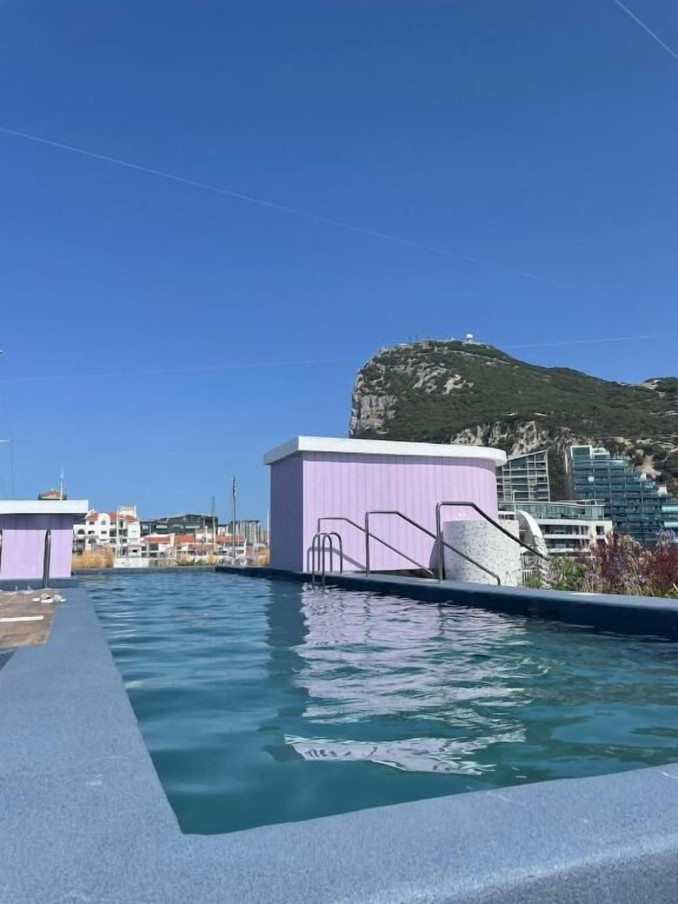 A swimming pool with a view of a mountain and buildings in the background.