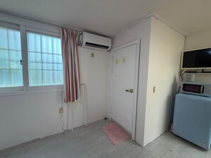 A room with a white door, a window with curtains, a small pink rug, a white radiator, and a blue appliance with a screen. - POOH_Serene studio with AC in charming Ewha Univ. (Seodaemun-gu,)