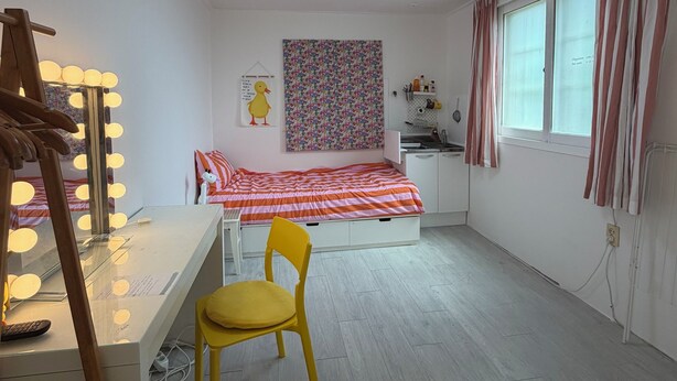 A bedroom with a bed, a desk with a chair, a vanity with lights, a window with curtains, and a wall with a poster. - POOH_Serene studio with AC in charming Ewha Univ. (Seodaemun-gu,)