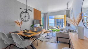 Een moderne woonkamer met een eethoek, grote ramen en uitzicht op de stad.