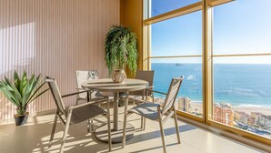Ein Balkon mit rundem Tisch und Stühlen, einer Topfpflanze und Blick auf den Ozean.